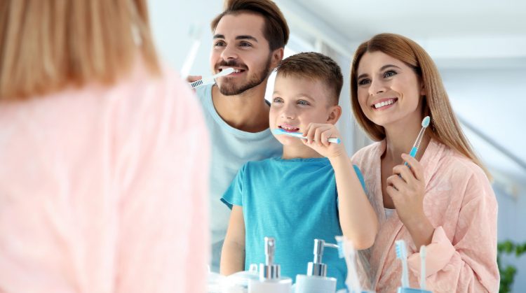 Smiling family brushing teeth together to prevent cavities in kids – Mark Michna, DDS