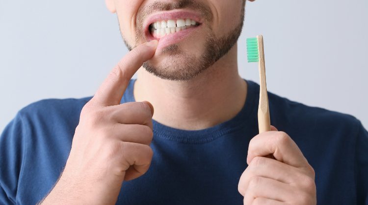 Man pointing to bleeding gums while holding a toothbrush – Mark Michna, DDS, Greenbrae, CA